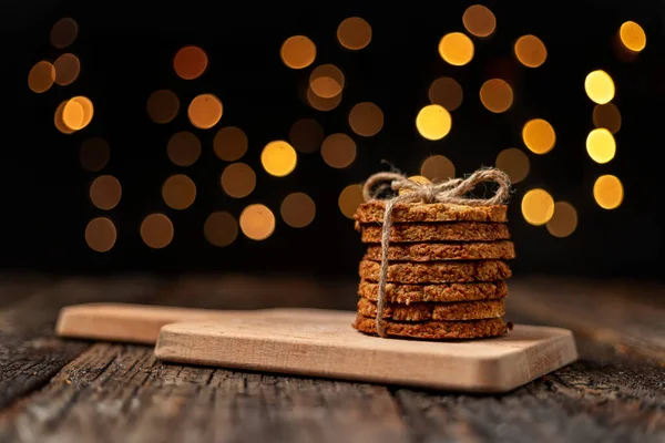Μια στοίβα βιολογικά μπισκότα βρώμης για τα Χριστούγεννα, με λαμπερά φώτα bokeh. Κοντινό πλάνο. — Φωτογραφία Αρχείου