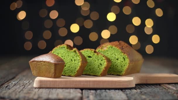 Pan de Navidad Stollen hecho de espirulina y pistachos, sin azúcar, dietético para las fiestas. En una mesa de madera, luces bokeh en el fondo. — Vídeos de Stock