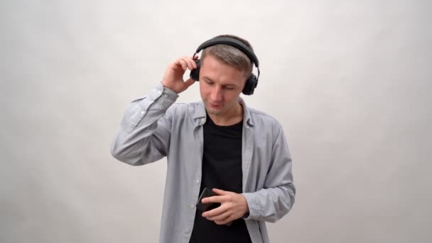헤드폰과 스마트폰으로 흰 배경을 가진 젊은 남자가 음악과 춤을 듣는다. 유럽에서 온 즐거운 감정들. — 비디오