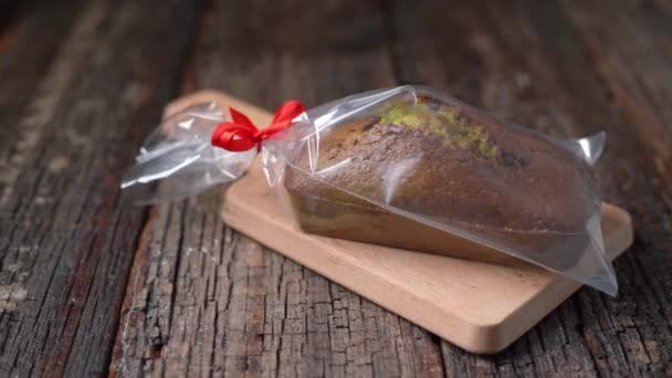Πρησμένο χριστουγεννιάτικο ψωμί από σπιρουλίνα και φιστίκια, χωρίς ζάχαρη, διαιτητικό για τις γιορτές. Συσκευασμένο σε πλαστική σακούλα ως δώρο. Σε ένα ξύλινο τραπέζι υφή. — Αρχείο Βίντεο