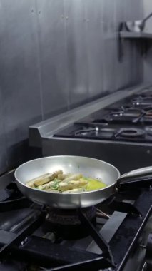Şef tavada sarımsaklı midye pişiriyor. Dikey video. Yakın plan..