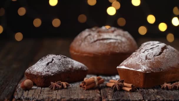 Trzy bożonarodzeniowe chleb, stollen, na drewnianym stole teksturowanym, na tle rozmytych świateł w bokeh. W Boże Narodzenie. — Wideo stockowe