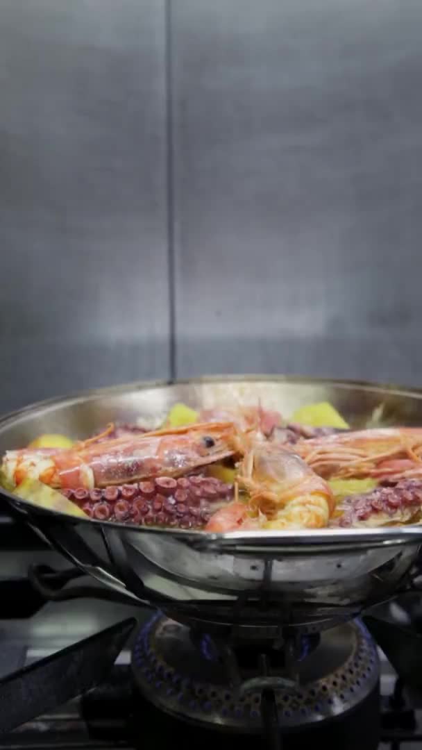 Chef cooks a cataplan with octopus, seafood, vegetables. Vertical video. Close-up. — Stock Video