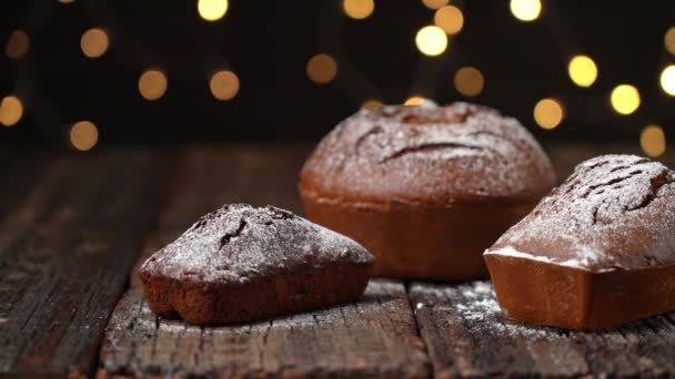 Trzy bożonarodzeniowe pieczywo stollen, stół, na drewnianym, teksturowanym stole, na tle rozmytych świateł w bokeh. Ruch boczny. — Wideo stockowe