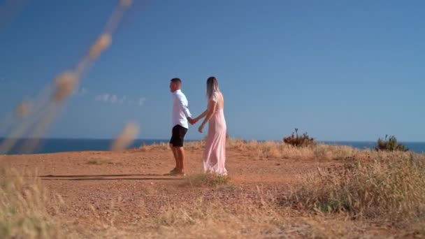 Een jong stel loopt langs de kust bij een romantische ontmoeting. Huwelijksreis. Valentijnsdag. — Stockvideo