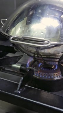 Deniz ürünleri pişirmek için gaz sobasının üzerine kataplan bakır tava. Dikey video. Yakın plan..