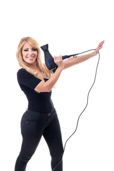 Side shot of hairdresser holding a hairdryer and smiling, wearing black clothing on a white background. Isolated — Stock Photo, Image