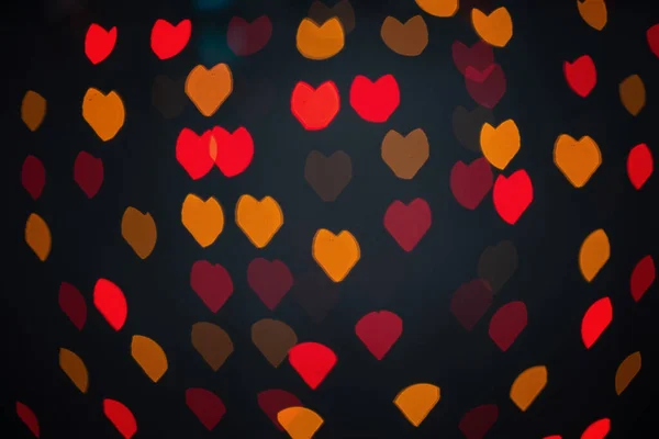Cuori sfocati multicolori, bokeh, luci su sfondo nero, simbolo d'amore per San Valentino. — Foto Stock