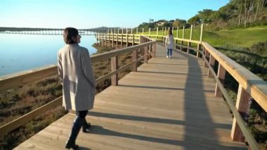 Nehir kıyısında sahil kenarında yürüyen iki kadın ve önünde insanlar var. Sao Lourenco Quinta de Lago, Almancil. Portekiz
