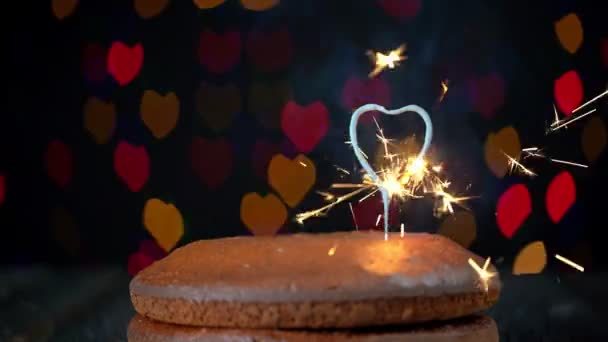 Mano accendendo cuore shapped sparkler posto su una semplice torta per festeggiare San Valentino. Sullo sfondo, luci sfocate, bokeh di cuori lampeggiano. — Video Stock