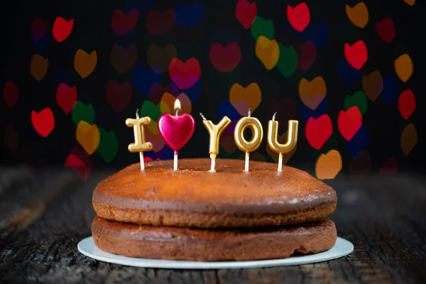 Основной торт с Я люблю вас свечи, сердце, помещены на винтажный стол и цветные рисунки боке на заднем плане. — стоковое фото