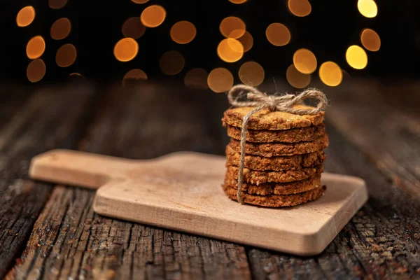 Una pila di biscotti biologici di farina d'avena per Natale, con luci incandescenti bokeh. Primo piano. — Foto Stock