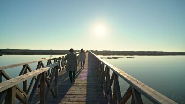 Dos hembras caminando en un paseo marítimo cerca de una orilla del río con gente adelante. Sao Lourenco Quinta de Lago, Almancil. Portugal — Vídeos de Stock