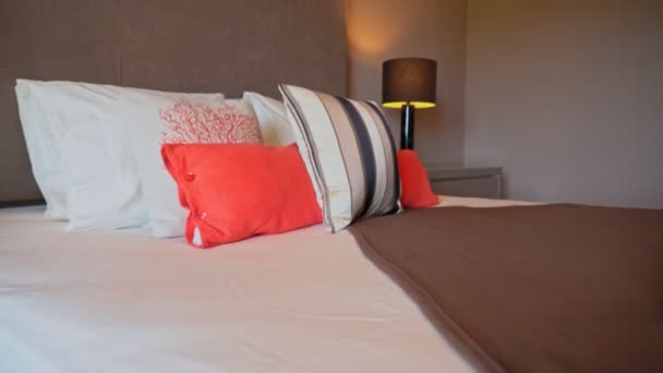 Μεγέθυνση σε μαξιλάρια που τοποθετούνται στο κρεβάτι σε ένα φυσικά καλά φωτισμένο και τακτοποιημένο σύγχρονο υπνοδωμάτιο. — Αρχείο Βίντεο