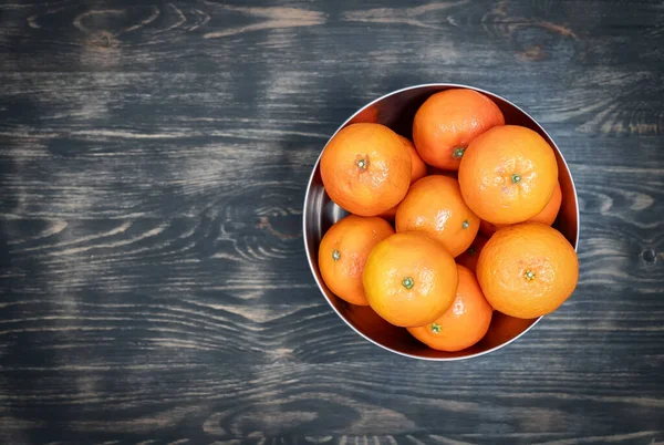 Vista superior de tangerinas brilhantes e suculentas dentro de uma tigela de metal colocada em cima de uma mesa. — Fotografia de Stock