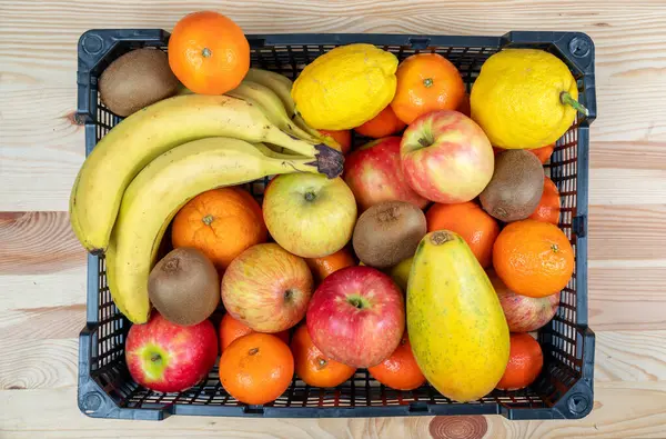 Top view of fruit basket with apples, bananas, oranges, lemons and kiwis, placed on a table. — Stock Photo, Image