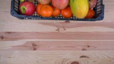 Bir adam, salgın sırasında bir kutuda tropikal meyve şeklinde bağış yaptı. Ahşap bir arka planda, üst manzara.