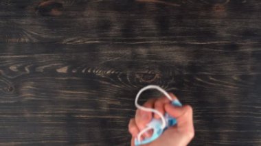Adamın eli ameliyat maskesini masaya fırlatıyor. Bir salgın sırasında hijyen ve izolasyon kurallarına uymamak..