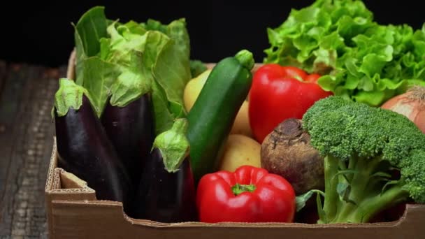 A box full of fresh vegetables on a dark background, wooden vintage table. In a panoramic motion. — Stock Video
