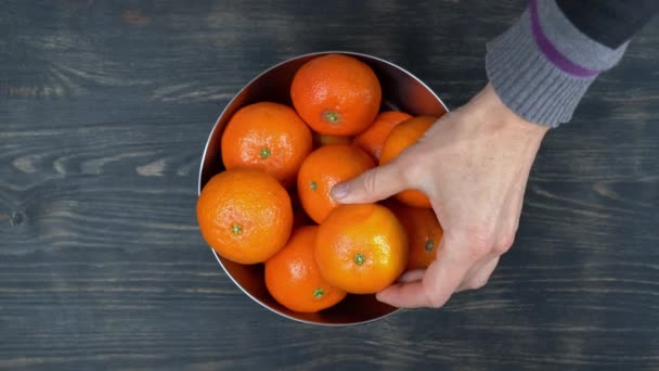 Vue de dessus, mains mans sont placés, un bol en métal avec des mandarines mûres, une source de vitamine c. Sur un fond en bois. — Video