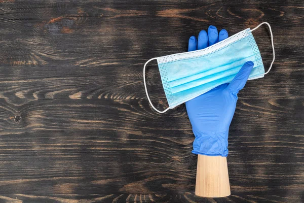 Mannequin hand wearing a disposable glove and holding a medical mask. During covid19 quarantine. — Stock Photo, Image