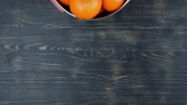Вид сверху, руки человека размещены, металлическая чаша с спелыми мандаринами, источник витамина С. На деревянном фоне. — стоковое видео