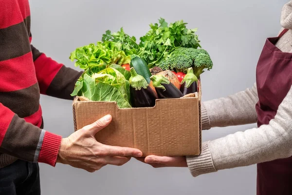 Een man krijgt een mand met producten van een vrouw. Allebei dragen ze maskers. Levering tijdens de Covid pandemie. — Stockfoto