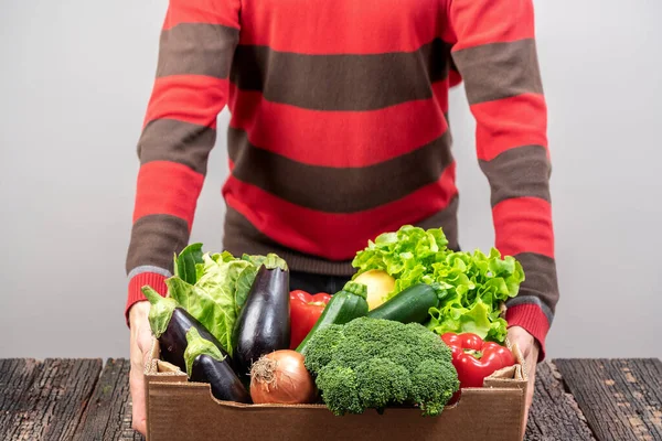 Un voluntario masculino entrega alimentos y verduras a las personas en cuarentena. Concepto de aislamiento doméstico. Entrega de comida para personas. Concepto de pandemia COVID-19 —  Fotos de Stock