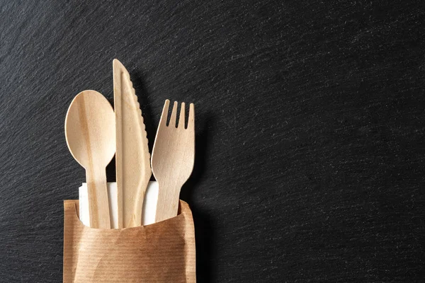 Disposable biodegradable tableware made of wood spoon, knife and fork on marble texture. Close-up. — Stock Photo, Image
