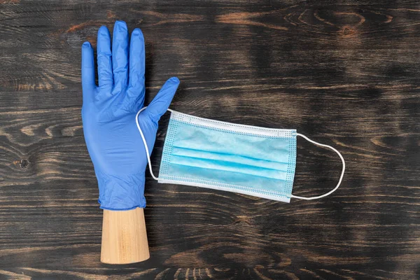 Mannequin hand wearing a disposable glove and holding a medical mask. During covid19 quarantine. — Stock Photo, Image