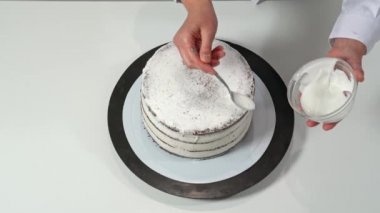 Pastanın kenarlarına erimiş beyaz çikolata döken bir fırıncının üst görüntüsü..