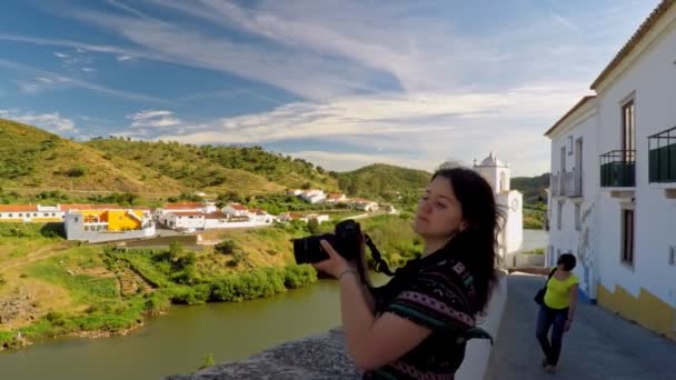 Városnézés Mertolában, Portugáliában egy lánnyal, aki a Guadiana folyót és egy szép zöld dombot fotózza. — Stock videók