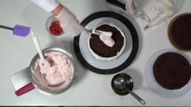 Şefin bir tabaka çikolatalı keki pembe kremayla doldurmasına bir bakış açısı..