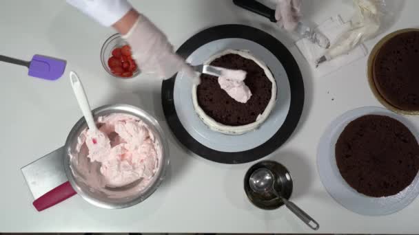 Přehled kuchaře plnění vrstva čokoládový dort s růžovou smetanou s pomocí některých nástrojů. — Stock video