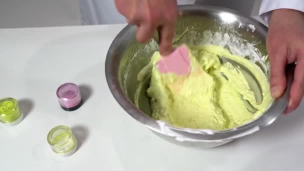Detailní záběr pekaře ruční míchání barevného těsta se silikonovou špachtlí připravit makarony. — Stock video