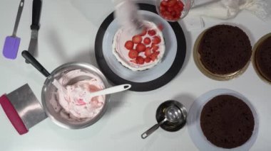 Şef pastaya dilimlenmiş çilek koyuyor. Üstüne de biraz krema dökülmüş..