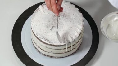 Pastanın kenarlarına erimiş beyaz çikolata döken bir fırıncının üst görüntüsü..