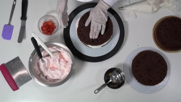 Baker çikolatalı pastanın yeni katmanını zaten dolu olan tabakanın üstüne yerleştiriyor ve kremayla süslemek için pasta poşeti kullanıyor.. — Stok video