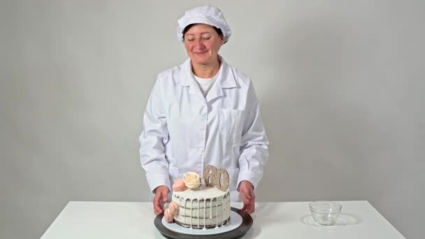 Prachtige verjaardagstaart, versierd met macarons en een roos, met trots gepresenteerd door een vrouwelijke bakker. — Stockvideo