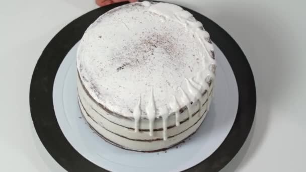Top view egy pék öntés olvadt fehér csokoládé a szélén a torta, így csöpög le az oldalán. — Stock videók