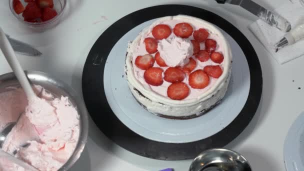 Foto frontal de un panadero usando una espátula de hielo para retocar cuidadosamente los lados de la torta cubierta de crema. — Vídeos de Stock