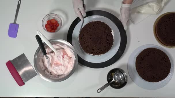 Prise de vue avant d'un boulanger à l'aide d'une spatule glaçante pour retoucher soigneusement les côtés du gâteau recouvert de crème. — Video