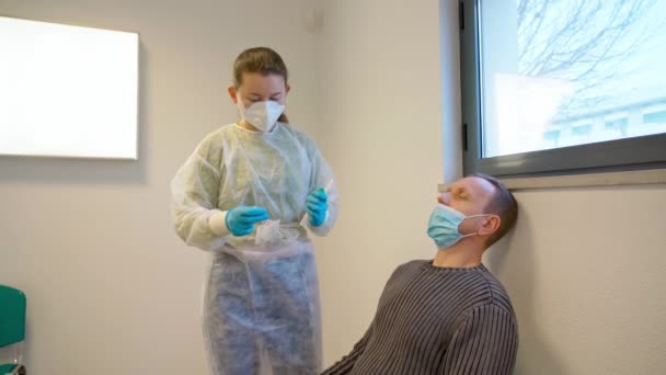 Medical Nurse in Gloves and Mask, test for suspected coronavirus diagnosis. Physician taking a nasofaringeal sample of a woman, with a cotton swab. Covid19 screening. — Stock Video