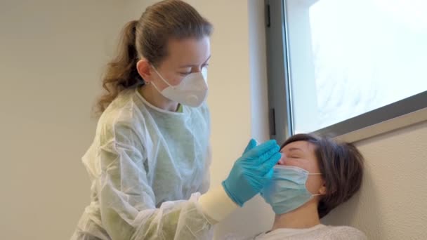 Sjuksköterska i handskar och mask, test för misstänkt koronavirusdiagnos. Läkare som tar ett nasofaringeal prov av en kvinna, med en bomullstuss. Mynt19 screening. — Stockvideo