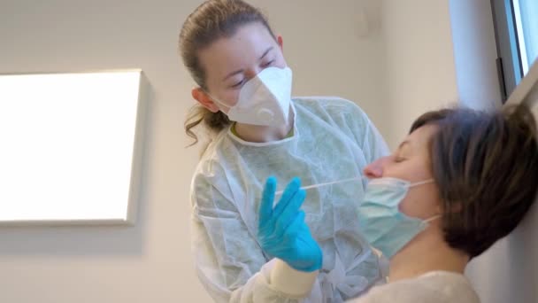 Sjuksköterska i handskar och mask, test för misstänkt koronavirusdiagnos. Läkare som tar ett nasofaringeal prov av en kvinna, med en bomullstuss. Mynt19 screening. — Stockvideo