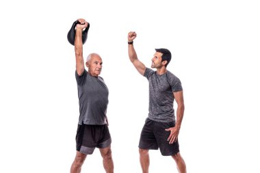 Spor hocasıyla egzersiz yapan yaşlı bir erkek müşteri, dambılı kaldırıyor. İzole edilmiş beyaz bir arkaplanda.