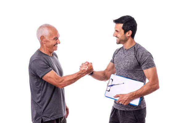 Cliente anziano maschio che stringe la mano nel saluto al fitness trainer prima dell'allenamento. Su uno sfondo bianco isolato. — Foto Stock