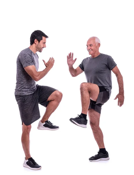 Adultos mayores de sexo masculino haciendo ejercicio con un entrenador de fitness, ejercicio caminar en su lugar, pasos. Sobre un fondo blanco aislado. — Foto de Stock