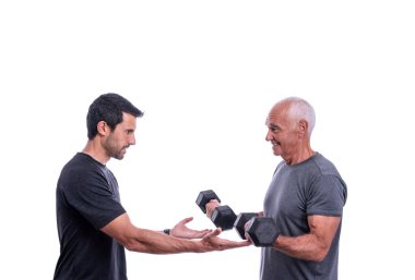 Spor hocasıyla egzersiz yapan yaşlı bir erkek müşteri, dambılları kaldırıyor. İzole edilmiş beyaz bir arkaplanda.