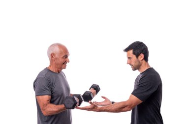 Spor hocasıyla egzersiz yapan yaşlı bir erkek müşteri, dambılları kaldırıyor. İzole edilmiş beyaz bir arkaplanda.